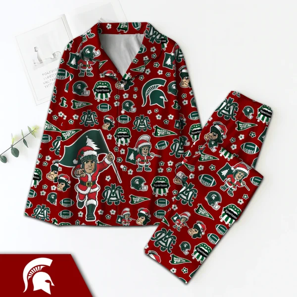 A festive Michigan Spartans satin pajama set in red with a Christmas pattern, laid flat on a white background next to a book.